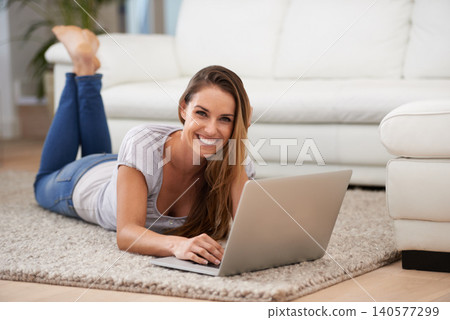 Woman, portrait and laptop on floor with internet for typing, communication and email on mat in living room of home. Person, smile or technology on ground with relax, streaming show or watching video 140577299