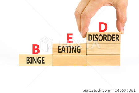 BED binge eating disorder symbol. Concept words BED binge eating disorder on beautiful wooden blocks. Beautiful white background. Doctor hand. Medical BED binge eating disorder concept. Copy space. BED binge eating disorder symbol. Concept words BED binge eating disorder on beautiful wooden blocks. Beautiful white background. Doctor hand. Medical BED binge eating disorder concept. Copy space. 140577391