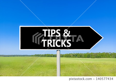 Tips and tricks words symbol. Concept words Tips and tricks on beautiful black road sign. Beautiful blue sky green field background. Business tips and tricks motivational support concept. Copy space. 140577434