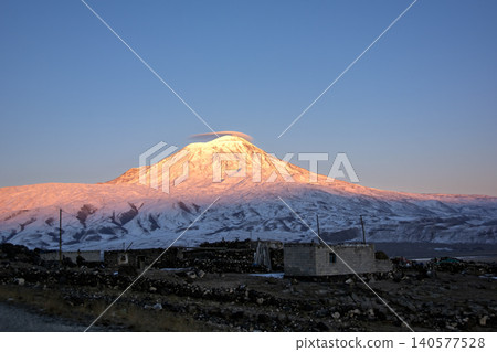 Majestic snow-capped Mount Ararat (Agri Dagi) at golden hour sunrise with a small rural village in the foreground, Turkey. 140577528