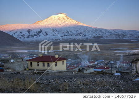 Majestic snow-capped Mount Ararat (Agri Dagi) at golden hour sunrise with a small rural village in the foreground, Turkey. 140577529