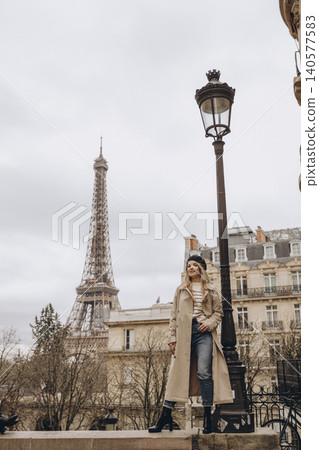 Stylish woman in trench coat posing near the Eiffel Tower in Paris Stylish woman in trench coat posing near the Eiffel Tower in Paris 140577583