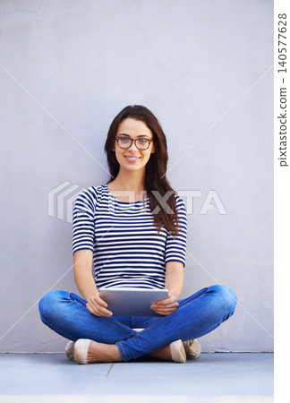 Portrait, smile and tablet for social media with woman on wall background for internet research. App, email and technology with happy young person legs crossed on floor for online information Portrait, smile and tablet for social media with woman on wall background for internet research. App, email and technology with happy young person legs crossed on floor for online information 140577628