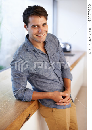 Smile, happiness and portrait of man in kitchen at home, house and apartment leaning on countertop. Interior, male person and homeowner relax on table in canteen, pantry and cooking area in Portugal Smile, happiness and portrait of man in kitchen at home, house and apartment leaning on countertop. Interior, male person and homeowner relax on table in canteen, pantry and cooking area in Portugal 140577690