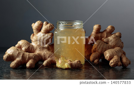 Ginger jam in jar and fresh ginger roots on a black background. Ginger jam in jar and fresh ginger roots on a black background. 140577833