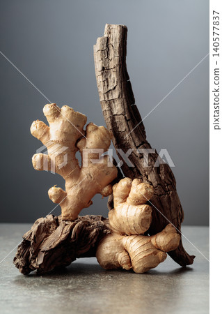Fresh ginger roots and old wooden snags on a stone table. Fresh ginger roots and old wooden snags on a stone table. 140577837