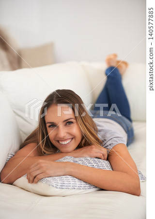 Woman, portrait and relax on sofa in living room, calm and comfort with positive mood for leisure. Rest, lying down with pillow and smile for stress relief, break on day off or weekend at home Woman, portrait and relax on sofa in living room, calm and comfort with positive mood for leisure. Rest, lying down with pillow and smile for stress relief, break on day off or weekend at home 140577885