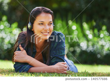 Grass, thinking and woman with headphones, listening to music and streaming audio with peace, relaxing and sunshine. Person in a park, outdoor and girl with headset and podcast with radio and sound Grass, thinking and woman with headphones, listening to music and streaming audio with peace, relaxing and sunshine. Person in a park, outdoor and girl with headset and podcast with radio and sound 140577886