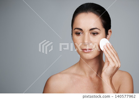 Mature woman, pad and cleanse in studio, skin care and facial treatment on gray background. Female person, cotton and swab for grooming in daily routine, mockup space and dermatology to remove makeup Mature woman, pad and cleanse in studio, skin care and facial treatment on gray background. Female person, cotton and swab for grooming in daily routine, mockup space and dermatology to remove makeup 140577962