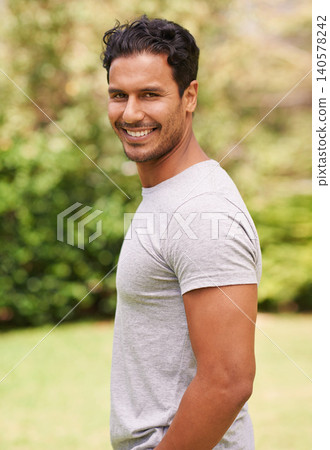 Man, outdoor and portrait on grass, smile and green, plants and garden in nature. Male person, backyard and fashion to relax, summer and vacation at garden or park for peace for wellness and happy 140578242
