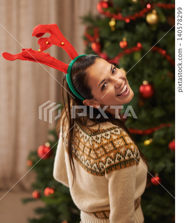Portrait, happy and woman in home for Christmas, party or holiday in apartment in Spain. Xmas, face and smile of female person in antlers for festive celebration, funny and laughing by tree in house Portrait, happy and woman in home for Christmas, party or holiday in apartment in Spain. Xmas, face and smile of female person in antlers for festive celebration, funny and laughing by tree in house 140578299