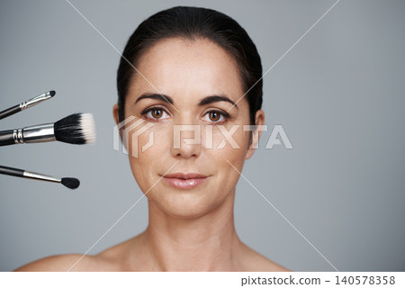 Makeup, brushes and portrait of woman in studio with beauty, natural and facial glow routine. Cosmetics, self care and mature female person with cosmetology tools isolated by gray background. Makeup, brushes and portrait of woman in studio with beauty, natural and facial glow routine. Cosmetics, self care and mature female person with cosmetology tools isolated by gray background. 140578358