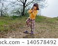 Young Girl Balancing on One Foot During Outdoor Play in Nature 140578492