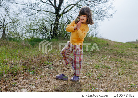 Young Girl Balancing on One Foot During Outdoor Play in Nature 140578492