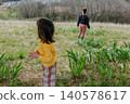 Two Children Exploring a Grassy Hillside in Nature 140578617