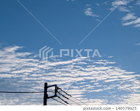 White clouds and the silhouette of a telephone pole spread across a blue sky / Background material depicting an everyday scene and a refreshing sky White clouds and the silhouette of a telephone pole spread across a blue sky / Background material depicting an everyday scene and a refreshing sky 140579025