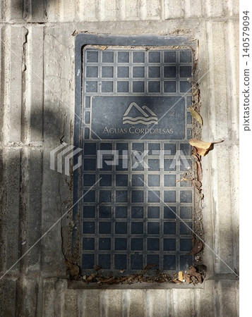 Cordoba, Argentina - April 9, 2026: Weathered Aguas Cordobesas manhole cover set into a sidewalk in Cordoba, Argentina Cordoba, Argentina - April 9, 2026: Weathered Aguas Cordobesas manhole cover set into a sidewalk in Cordoba, Argentina 140579094