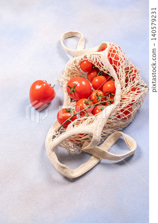Fresh tomatoes in reusable mesh shopping bag on light surface 140579231
