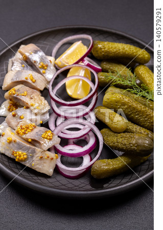 Marinated herring fillets with pickles, red onion, and lemon Marinated herring fillets with pickles, red onion, and lemon 140579291