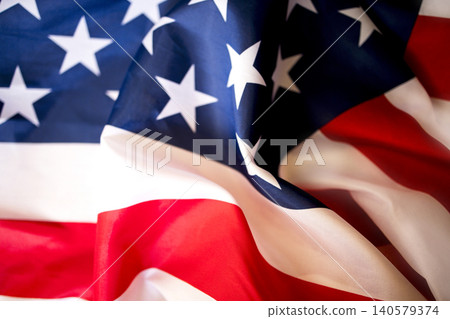 American flag fabric with red and white stripes and blue field featuring white stars, displaying vibrant colors and intricate folds in the textile 140579374
