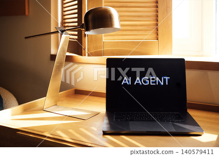 Laptop displaying text "AI AGENT" on a wooden desk with a modern lamp and window light illuminating the workspace in a contemporary office setting Laptop displaying text "AI AGENT" on a wooden desk with a modern lamp and window light illuminating the workspace in a contemporary office setting 140579411