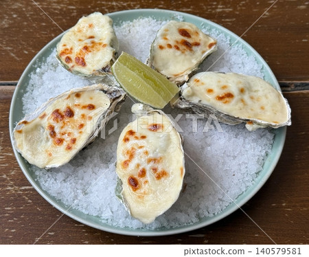 Baked Oysters with Melted Cheese Served on Ice and Lime Wedge at Seafood Restaurant Baked Oysters with Melted Cheese Served on Ice and Lime Wedge at Seafood Restaurant 140579581