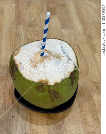 Fresh Green Coconut with Drinking Straw Served on Wooden Table Tropical Refreshment Fresh Green Coconut with Drinking Straw Served on Wooden Table Tropical Refreshment 140579597