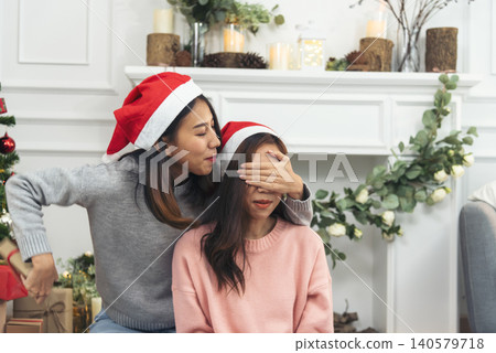 Two Women siblings using hands decorate Christmas tree red ball, bauble, snow flake. Close up hands holding red ball bauble decorate. Asian woman friends decor bauble ball christmas tree xmas holiday 140579718