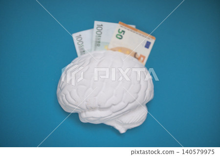 White brain model with euro banknotes partially inserted, placed on a blue background, symbolizing financial intelligence and investment concepts White brain model with euro banknotes partially inserted, placed on a blue background, symbolizing financial intelligence and investment concepts 140579975