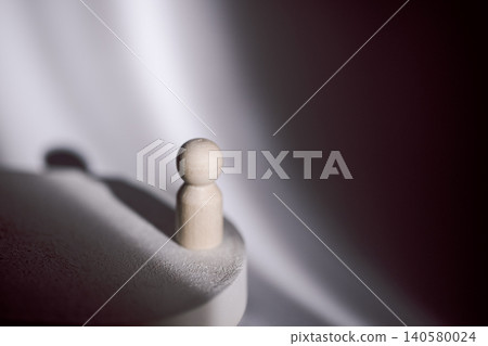 Wooden figure standing on a circular base with soft shadows and a smooth fabric background creating a minimalist aesthetic in a studio setting Wooden figure standing on a circular base with soft shadows and a smooth fabric background creating a minimalist aesthetic in a studio setting 140580024