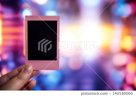 Hand holding a pink photo frame with a blank space against a vibrant bokeh background, symbolizing creativity, memories, and the art of photography in a colorful environment Hand holding a pink photo frame with a blank space against a vibrant bokeh background, symbolizing creativity, memories, and the art of photography in a colorful environment 140580060
