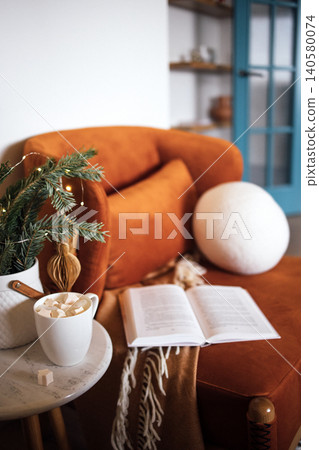 Cozy living room scene featuring an orange velvet sofa, a warm blanket, a cup of hot chocolate with marshmallows, and an open book on a marble table, creating a relaxing atmosphere Cozy living room scene featuring an orange velvet sofa, a warm blanket, a cup of hot chocolate with marshmallows, and an open book on a marble table, creating a relaxing atmosphere 140580074