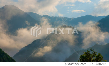 A sea of clouds and mist flowing through the mountains: A breathtaking morning scene in the deep mountains of Japan. A sea of clouds and mist flowing through the mountains: A breathtaking morning scene in the deep mountains of Japan. 140580203