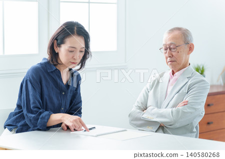 一位老人正在筆記本上寫字。 140580268