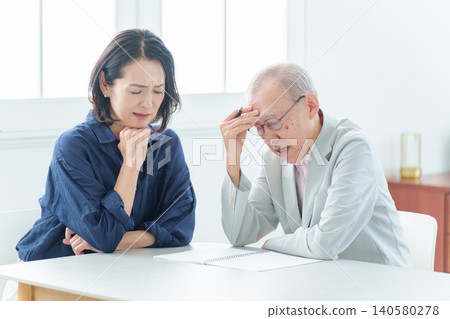 一位老人正在筆記本上寫字。 一位老人正在筆記本上寫字。 140580278