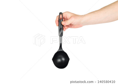 black plastic kitchen ladle in a hand on a white background 140580410