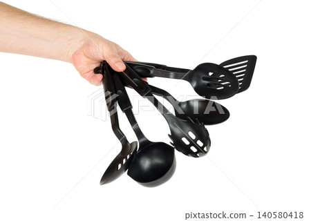 a whole set of black kitchen utensils in one male hand on a white background a whole set of black kitchen utensils in one male hand on a white background 140580418