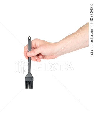 male hand holds a black silicone brush vertically down on a white isolated background male hand holds a black silicone brush vertically down on a white isolated background 140580428