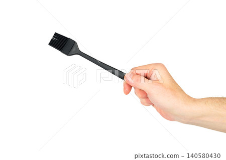 male hand holds a black silicone culinary brush with bristles up on a white background male hand holds a black silicone culinary brush with bristles up on a white background 140580430