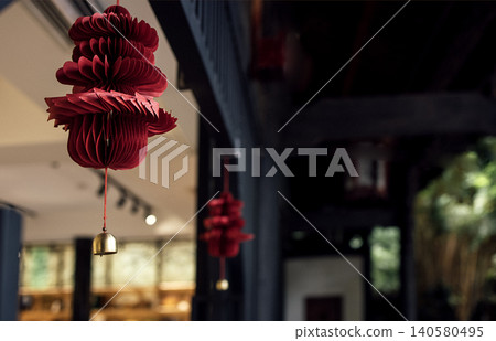 Red paper lantern decorations hanging indoors, showcasing intricate design and vibrant color, with blurred background elements of a traditional setting Red paper lantern decorations hanging indoors, showcasing intricate design and vibrant color, with blurred background elements of a traditional setting 140580495