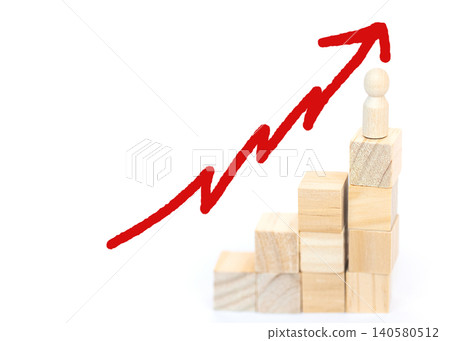 Wooden blocks arranged in a staircase formation with a small figure on top, accompanied by a red upward arrow symbolizing growth and progress in a business context 140580512
