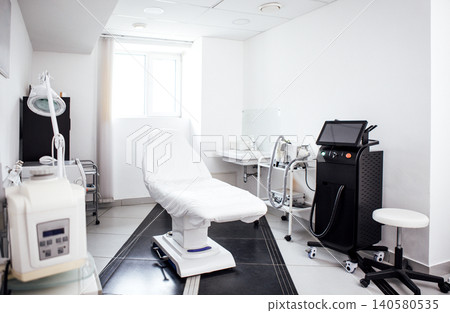 Modern aesthetic treatment room featuring a comfortable examination chair, advanced medical equipment, and bright natural light creating a welcoming atmosphere for clients seeking beauty services Modern aesthetic treatment room featuring a comfortable examination chair, advanced medical equipment, and bright natural light creating a welcoming atmosphere for clients seeking beauty services 140580535