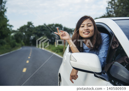 Happy asian women drive new car. Women Hand give remote control car key to man rental car service. Close up hands young woman showing new car key. Women driver giving car rental service smiling face 140580939