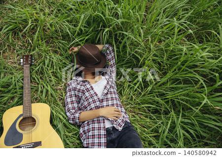 Young women playing acoustic guitar outdoor in green park. Woman person playing acoustic guitar music instrument at home, young Asian musician girl lifestyle in beautiful nature. Happy guitarist 140580942