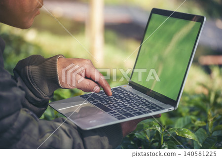 Smart farmer using laptop in eco green farm sustainable quality control. Close up Hand typing laptop computer quality control plant tree. Farmer hands using technology in eco Farmland biotechnology Smart farmer using laptop in eco green farm sustainable quality control. Close up Hand typing laptop computer quality control plant tree. Farmer hands using technology in eco Farmland biotechnology 140581225