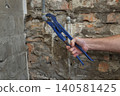 Plumber fixing old pipes in a bathroom using adjustable wrench 140581425