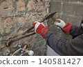 Plumber replacing old pipes in a bathroom, using hammer and chisel, closeup of hands with tool 140581427
