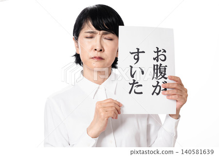 A middle-aged woman, looking dejected, was holding a piece of paper that read "I'm hungry." A middle-aged woman, looking dejected, was holding a piece of paper that read "I'm hungry." 140581639