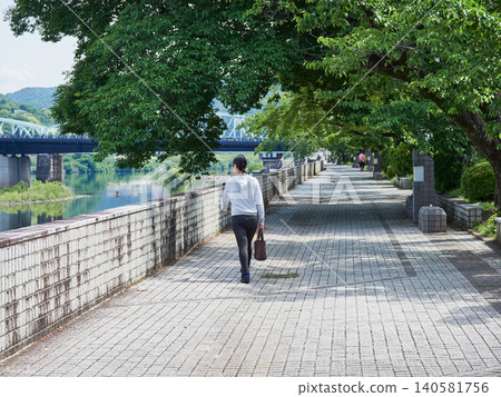 夏日清晨，一位年輕女子沿著犬山市木曾川河畔步道漫步。 140581756