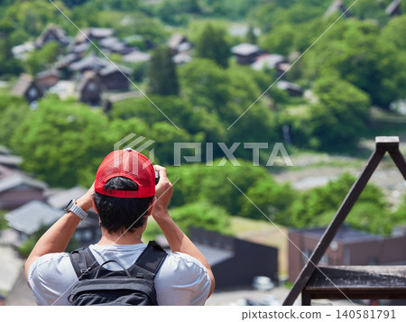 Tourists enjoying the scenery from an observation deck in Shirakawa-go, a World Heritage site and popular tourist spot in early summer. 140581791